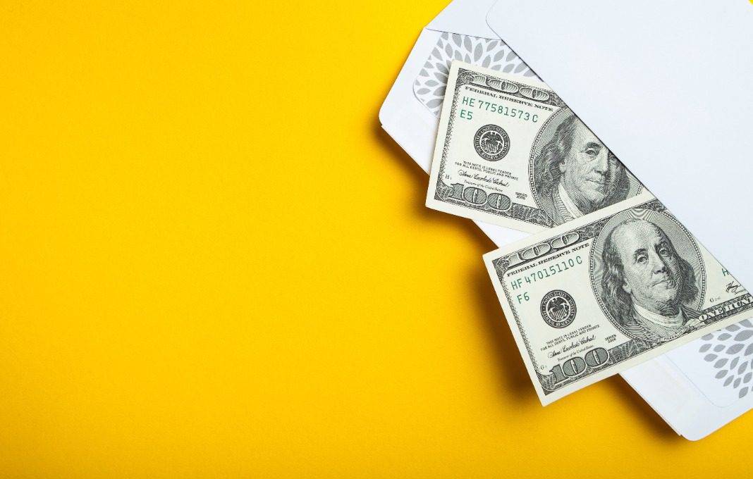 Two hundred dollar bills in an envelope on a yellow background