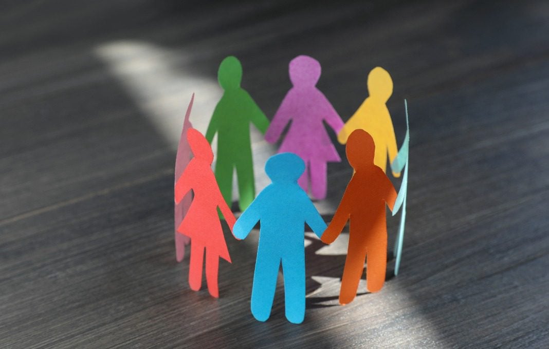 Paper human figures making circle on wooden table