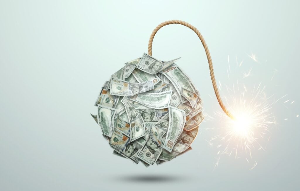 Bomb from money banknotes with a burning wick against white background.