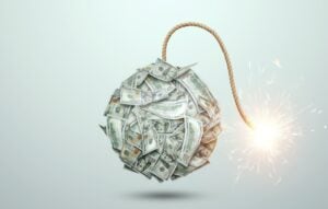 Bomb from money banknotes with a burning wick against white background.