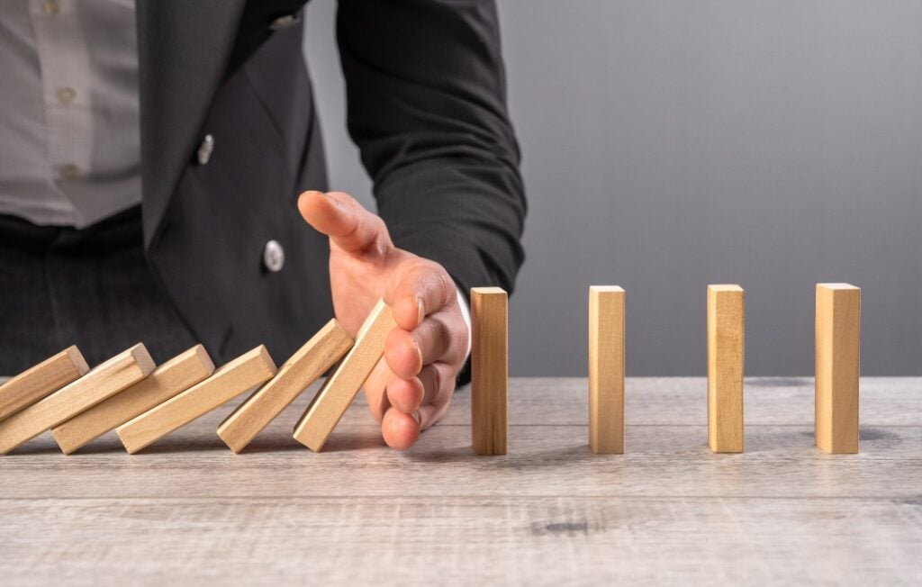 Hand stopping dominoes from falling