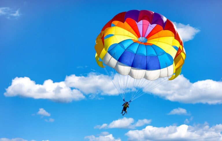 Gliding using a parachute on the background of cloudy blue sky.