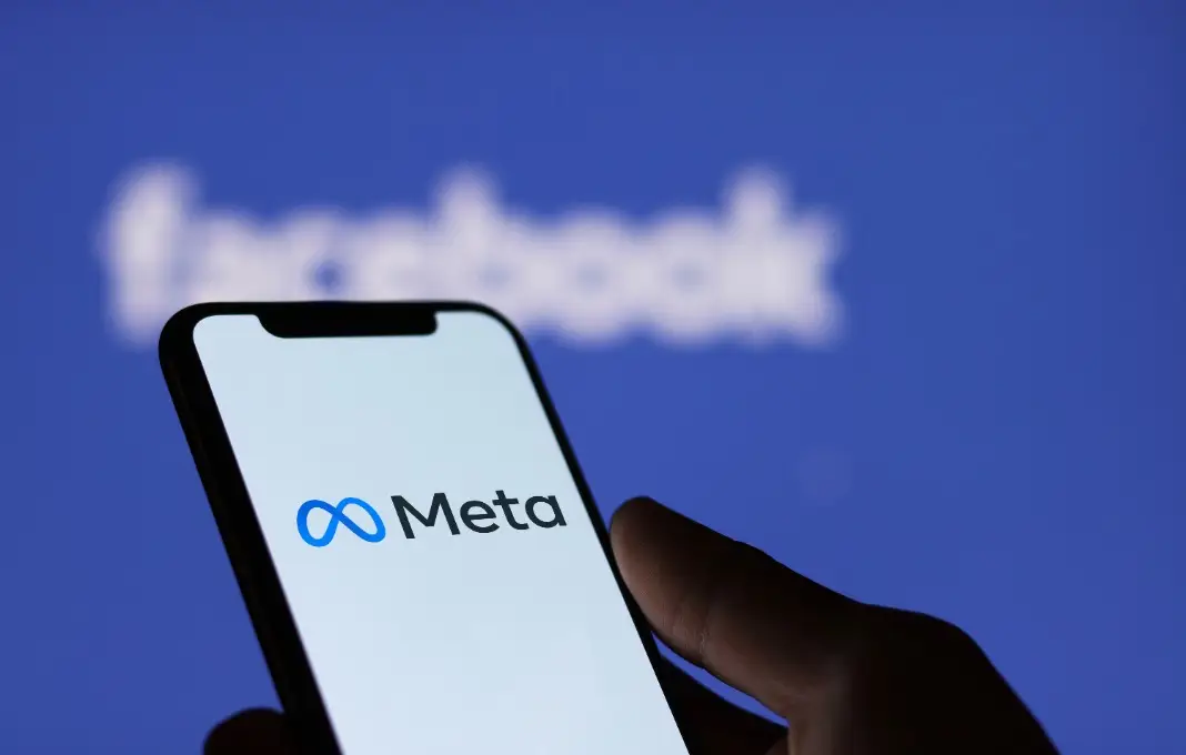 Hand holding phone with Meta logo on the screen