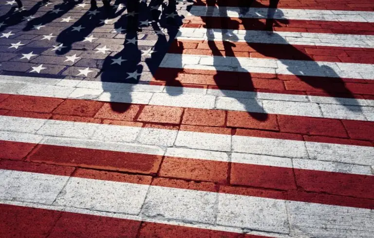Shadows of group of people walking through the streets with painted Usa flag on the floor.