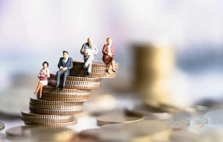 Miniature people sitting on coins stack.