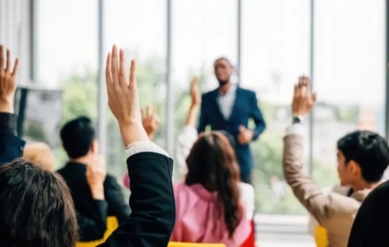 In a conference and convention at a corporate event businesspeople raise their hands to ask questions