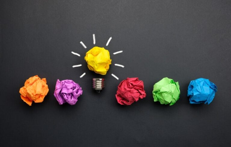 crumpled balls of colored paper, with yellow ball turned into a lightbulb