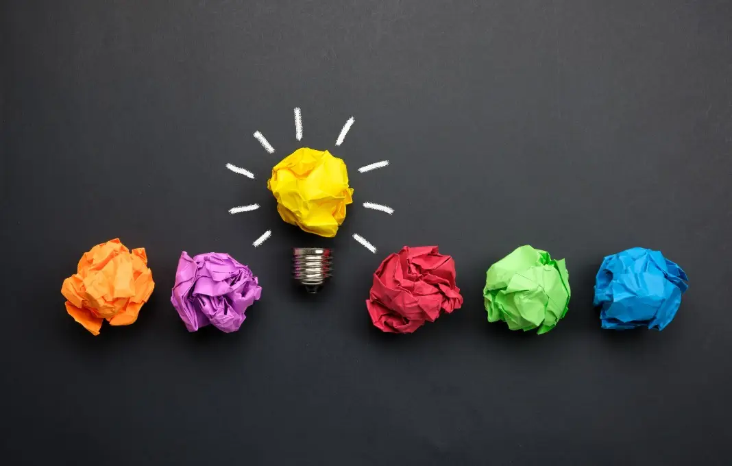 crumpled balls of colored paper, with yellow ball turned into a lightbulb
