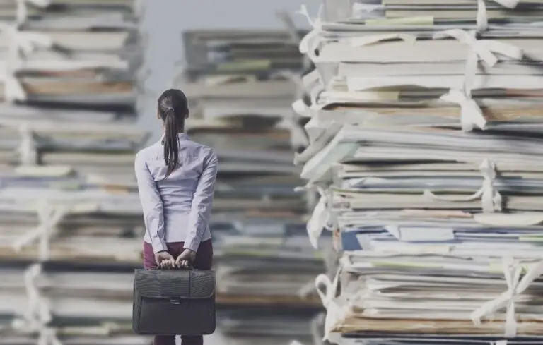 Frustrated businesswoman looking at piles of paperwork