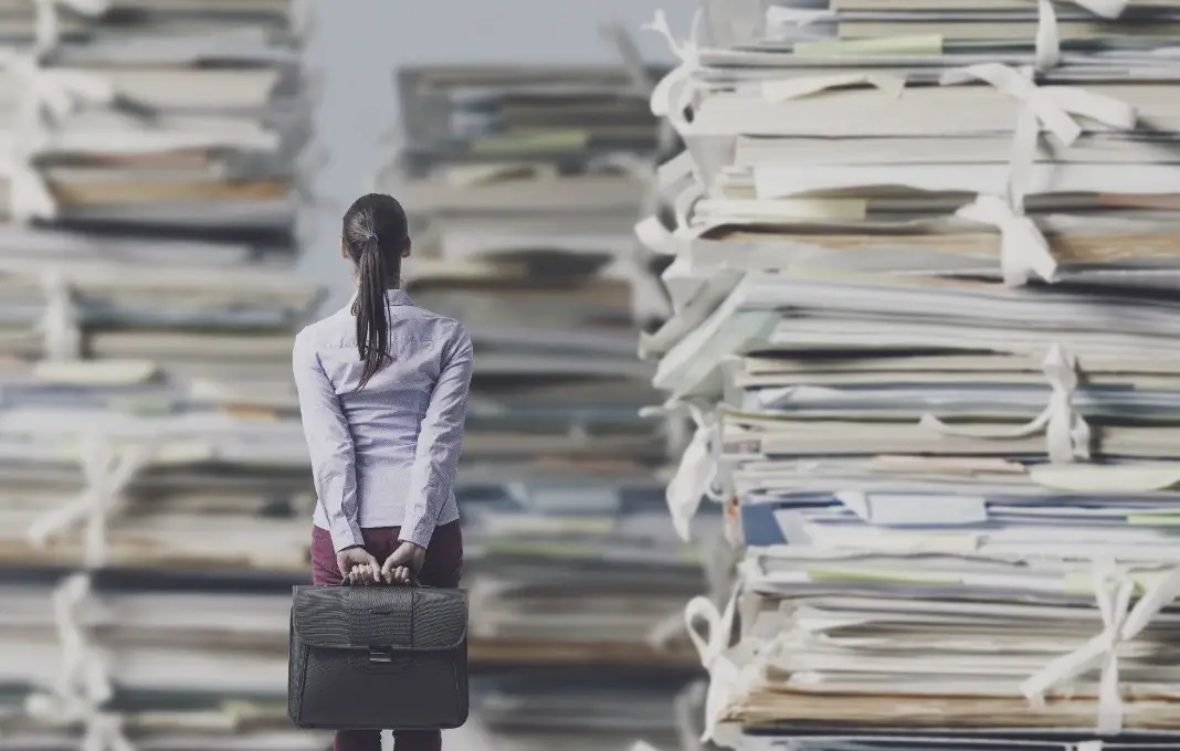 Frustrated businesswoman looking at piles of paperwork